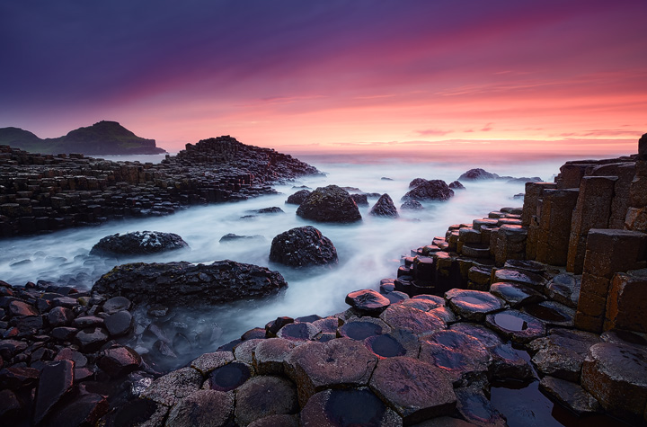 Hexagonal rocks, foglike water and a colorful sky.