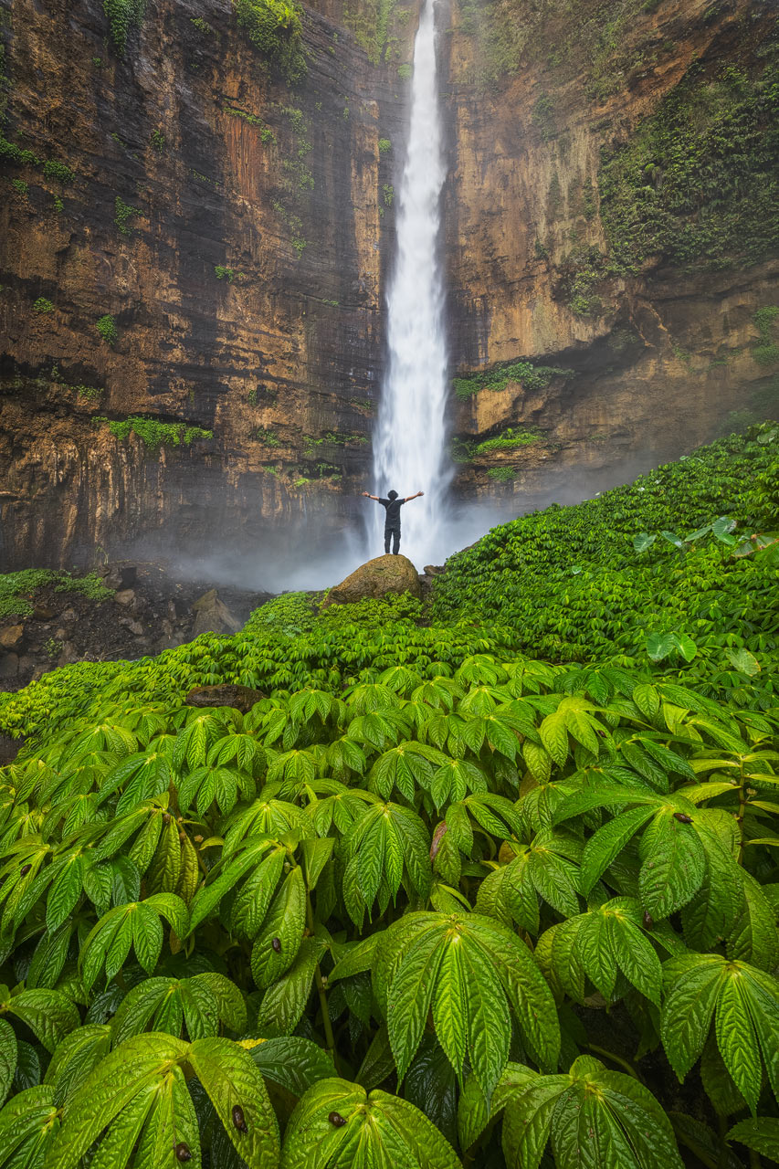 Kapas Biru Person standing in front of the mighty Kapas Biru waterfall on Java island