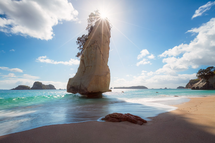 The sun behind sail rock at Cathedral Cove