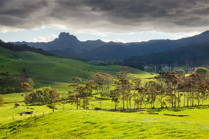 Green rolling hills, a mountain line and a stormy sky