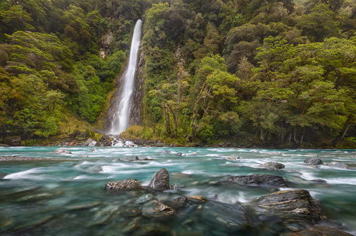 Lush green forest, deep blue river and a spectacular waterfall