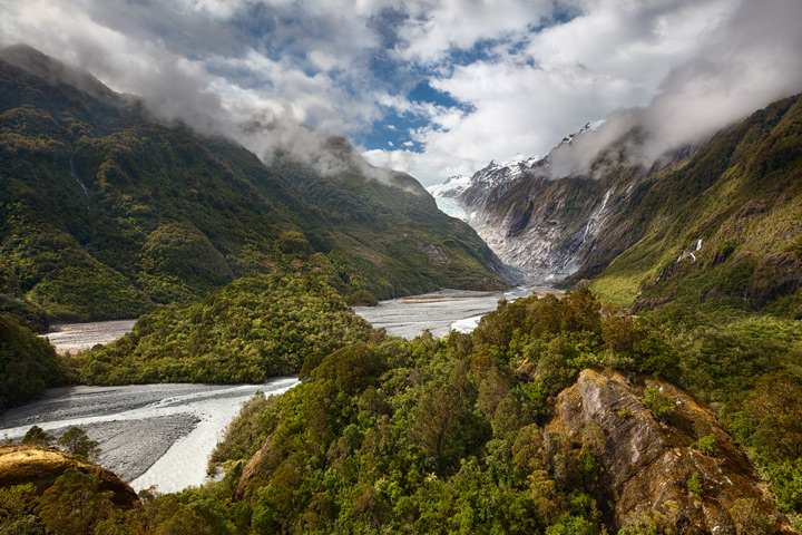 Franz Josef Glacier with the rainforest in the foreground on a sunny day