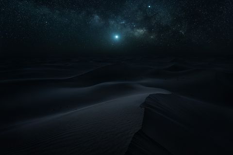 Desert Nights Starry night sky over dark sand dunes in a desert.