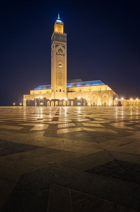 Hassan II Mosque Night view of the illuminated Hassan II Mosque with tall minaret and patterned open courtyard in Casablanca, Morocco.