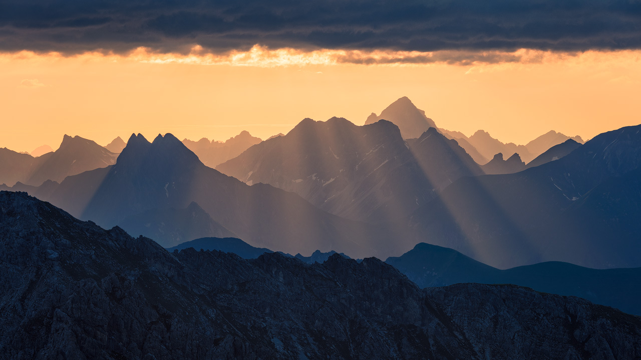 Sonnenstrahlen erleuchten die Allgäuer Alpen.