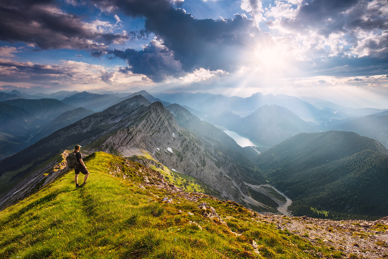 Ein Wanderer auf einem Kamm in den Alpen blickt zum Plansee.