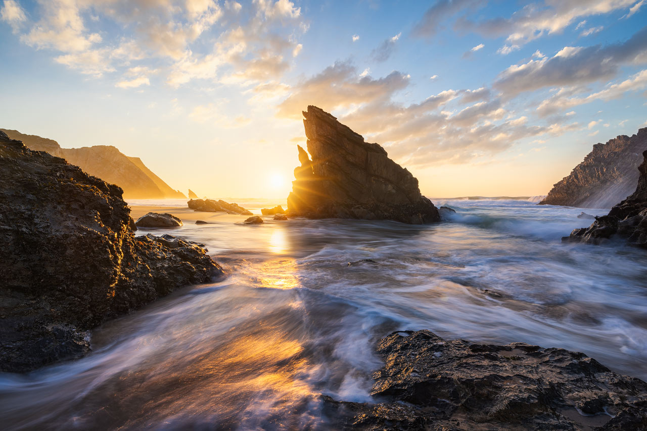 Die Sonne erleuchtet die Felsen am Praia da Adraga vor Sonnenuntergang