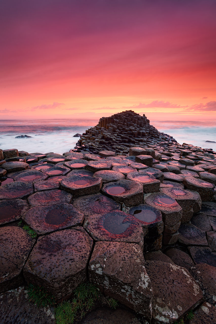 Die hexagonalen Felsen des Giants Causeway in Nordirland unter einem blutroten Himmel.