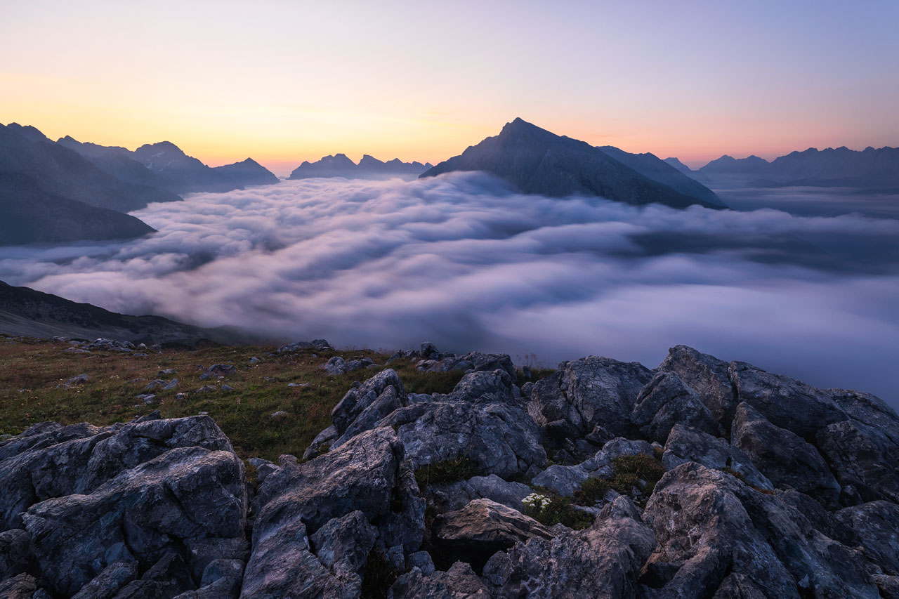 The sky glows above a cloud-covered valley in the Karwendel mountains.