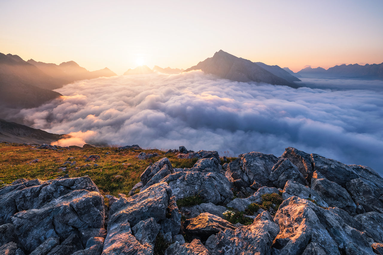 A sea of clouds covers the lower valleys of the Karwendel region during sunrise.